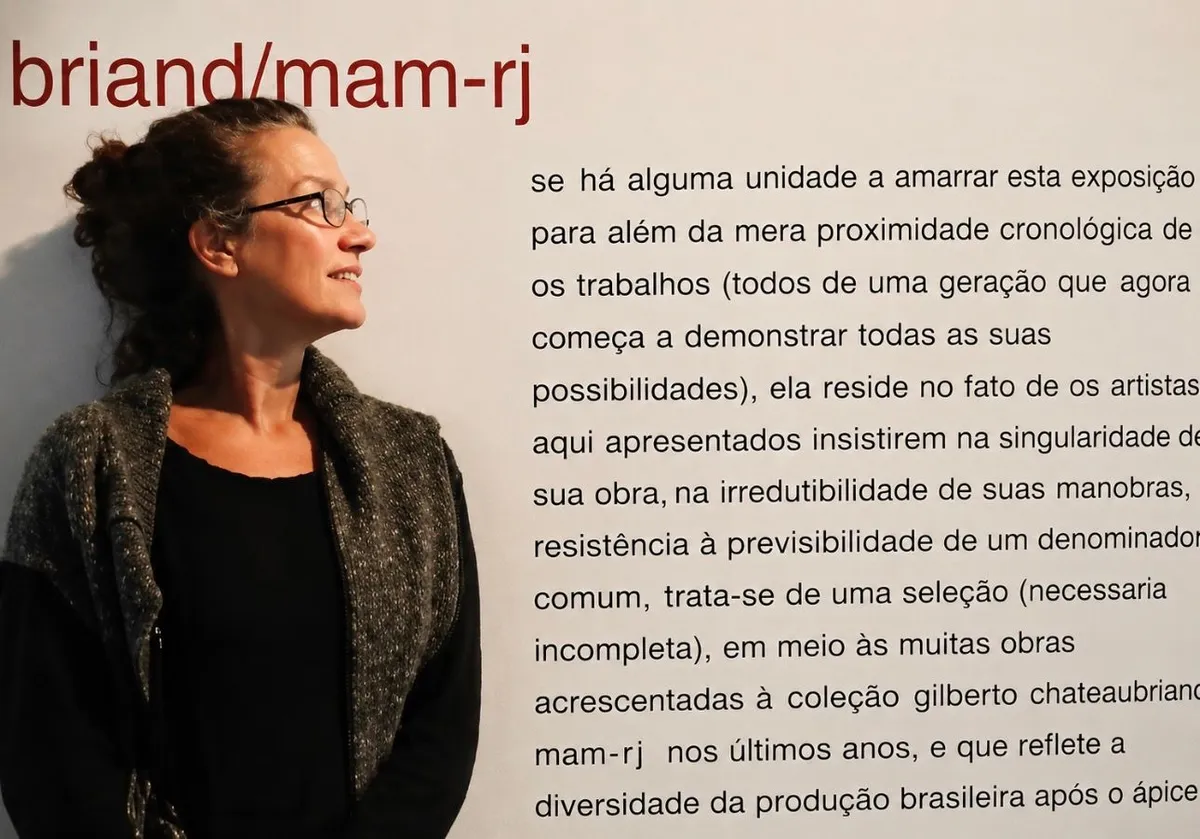 Frame do filme — MAM Rio, 1998

Eliane Duarte diante do texto curatorial da exposição Anos 90 na Coleção Gilberto Chateaubriand, MAM Rio, 1998.

Este frame de Flor de Lótus ganha especial força histórica: Eliane aparece inscrita, literalmente, no contexto crítico de sua própria geração. Ao fundo, o texto da exposição afirma que aqueles artistas “insistem na singularidade de sua obra” e na resistência a um denominador comum — uma formulação que ilumina a posição singular de Eliane dentro da produção brasileira dos anos 1990.

Sua presença na mostra é documentada nas referências de sua trajetória, ao lado de artistas que constituíram um dos núcleos decisivos da arte contemporânea brasileira. A importância desse recorte seria posteriormente consolidada pelo crítico e curador Luiz Camillo Osorio no volume Coleção Gilberto Chateaubriand: anos 90, 00 e novíssimos.

A dimensão institucional também é fundamental: críticos e curadores como Fernando Cocchiarale e Franz Manata definiriam a Coleção Gilberto Chateaubriand como uma espécie de “enorme jazida da arte brasileira”, capaz de produzir sucessivas leituras da história da arte no país.

Assim, o arquivo cinematográfico de Flor de Lótus não preserva somente a memória de Eliane Duarte: preserva, por dentro, um momento da história da arte contemporânea brasileira e a artista ocupando o lugar que lhe pertencia nessa história.

Frame de Eliane Duarte — Flor de Lótus. MAM Rio, 1998. Acervo audiovisual: Paulo Duarte / Guajupiá Filmes.